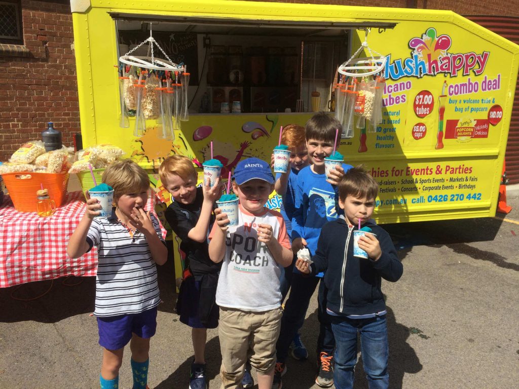 Children holding drinks in front of slushhappy bus